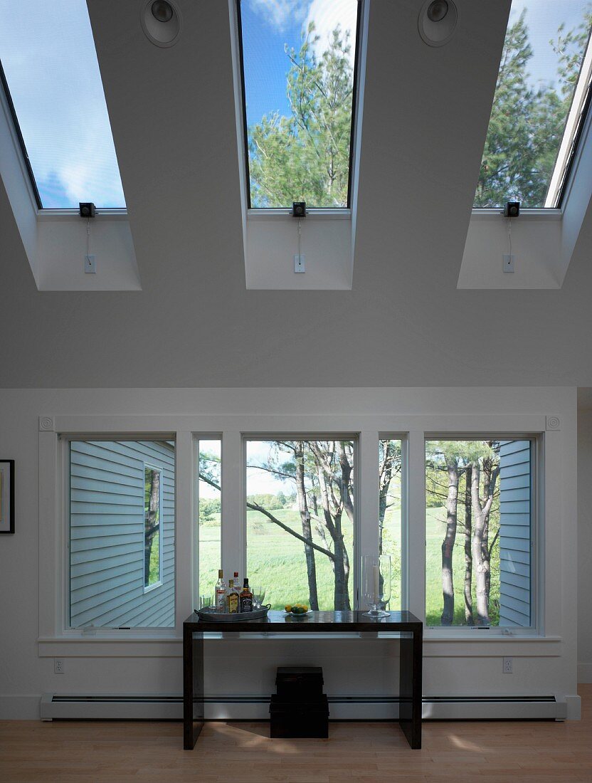 Black console table in front of window and under skylights in contemporary house