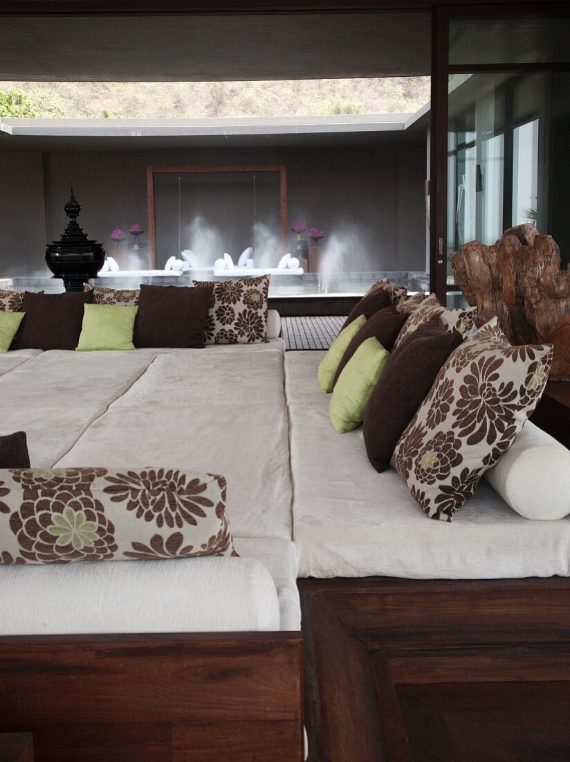 Spacious lounging platform with cushions and view into spa area with fountains
