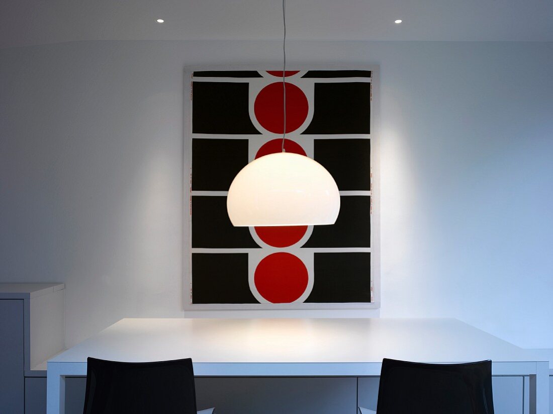 Lamp with white shade hanging above dining table