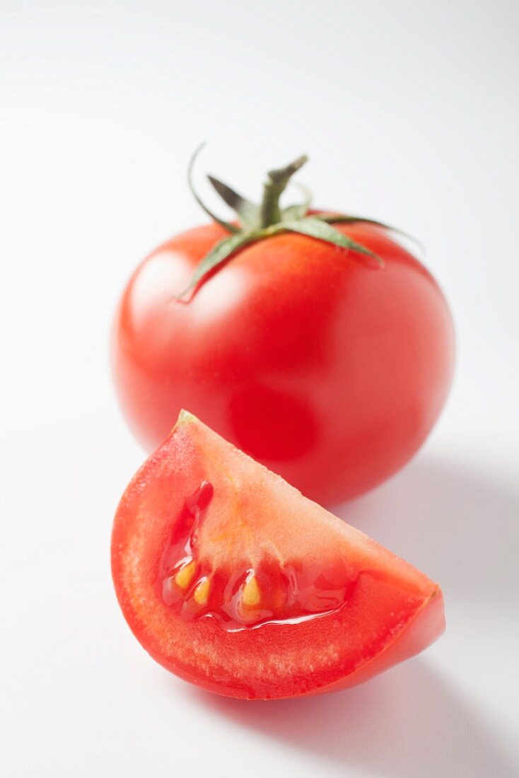 A slice of tomato and a whole tomato