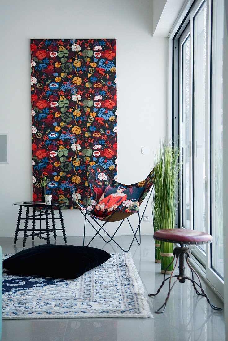 A well-lit corner of a room with a classic butterfly chair and a matching painting