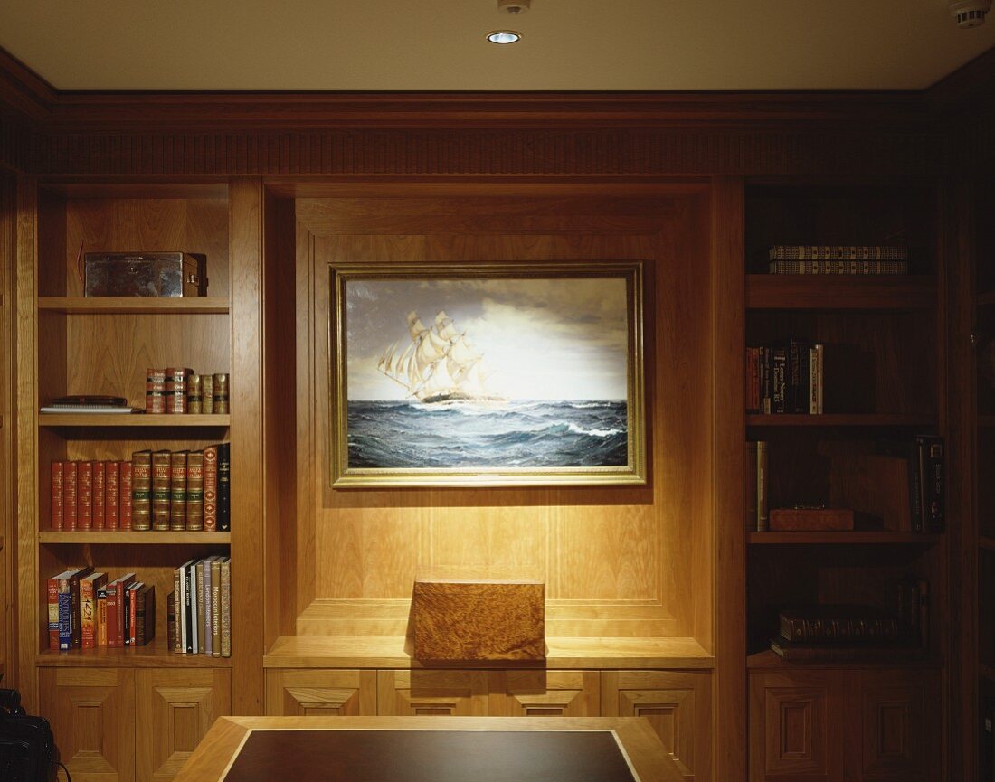 Wood-panelled wall with illuminated picture in niche and integrated shelves