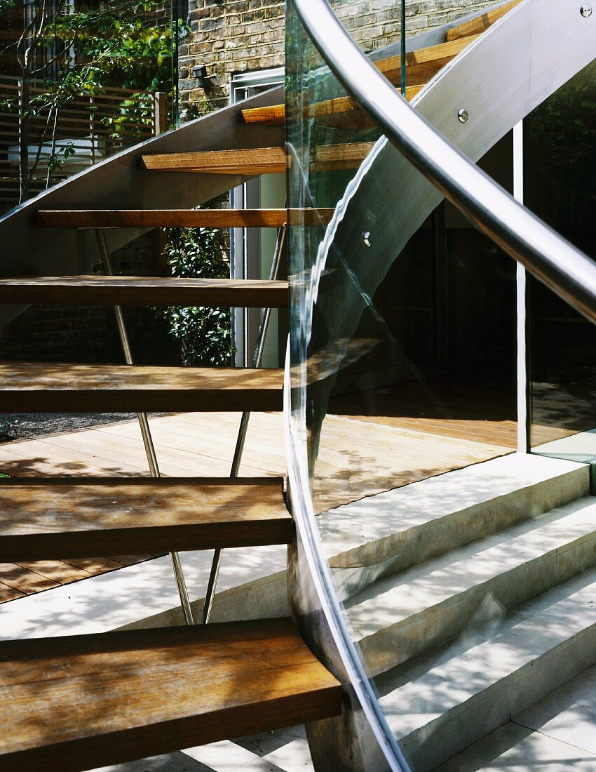 Curved staircase in courtyard with stainless steel stringer and wooden treads