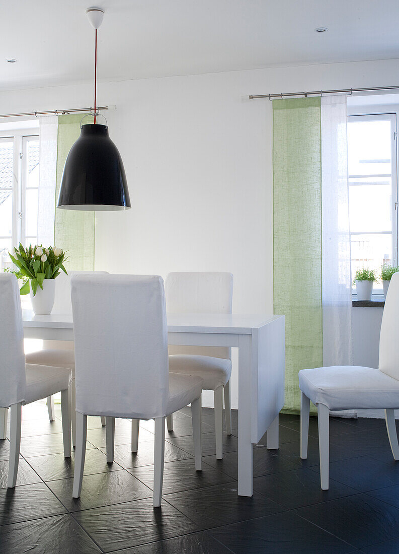 Dining area with white table, chairs and green curtains