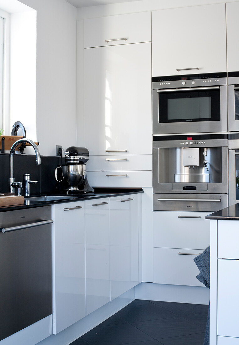 Modern kitchen with built-in appliances, white cupboards and black worktop