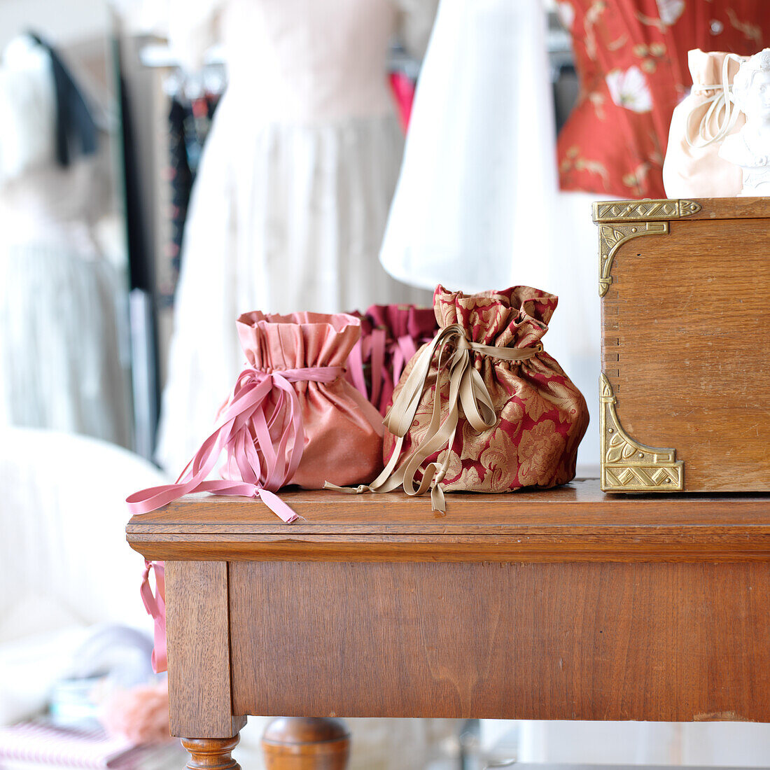 Cloth bag on wooden side table, clothes in the background