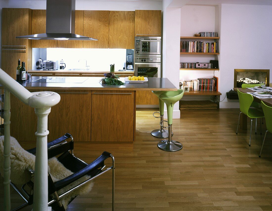 Open-plan kitchen with island and designer bar stools with green shell seats