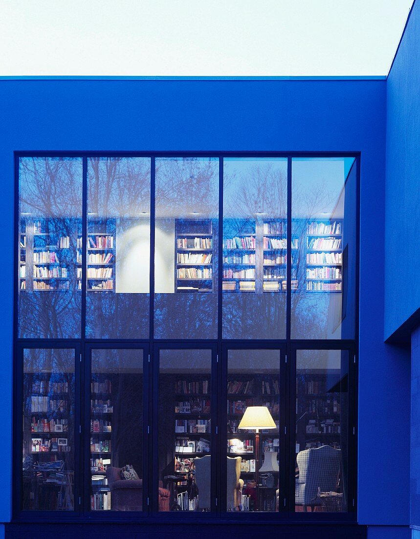 Contemporary house with glass facade and view of bookcases through windows