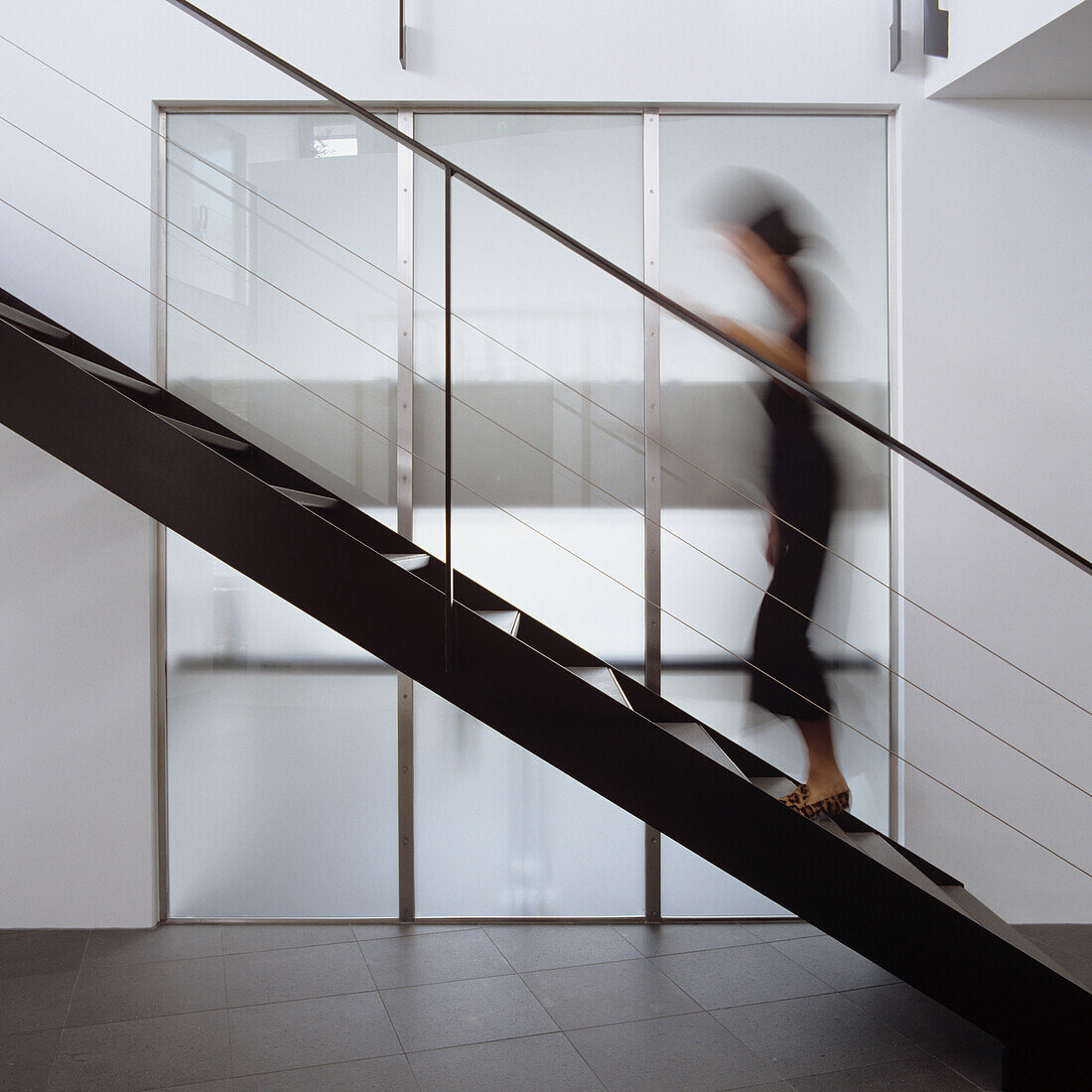 Modern staircase design with glass wall and person in motion