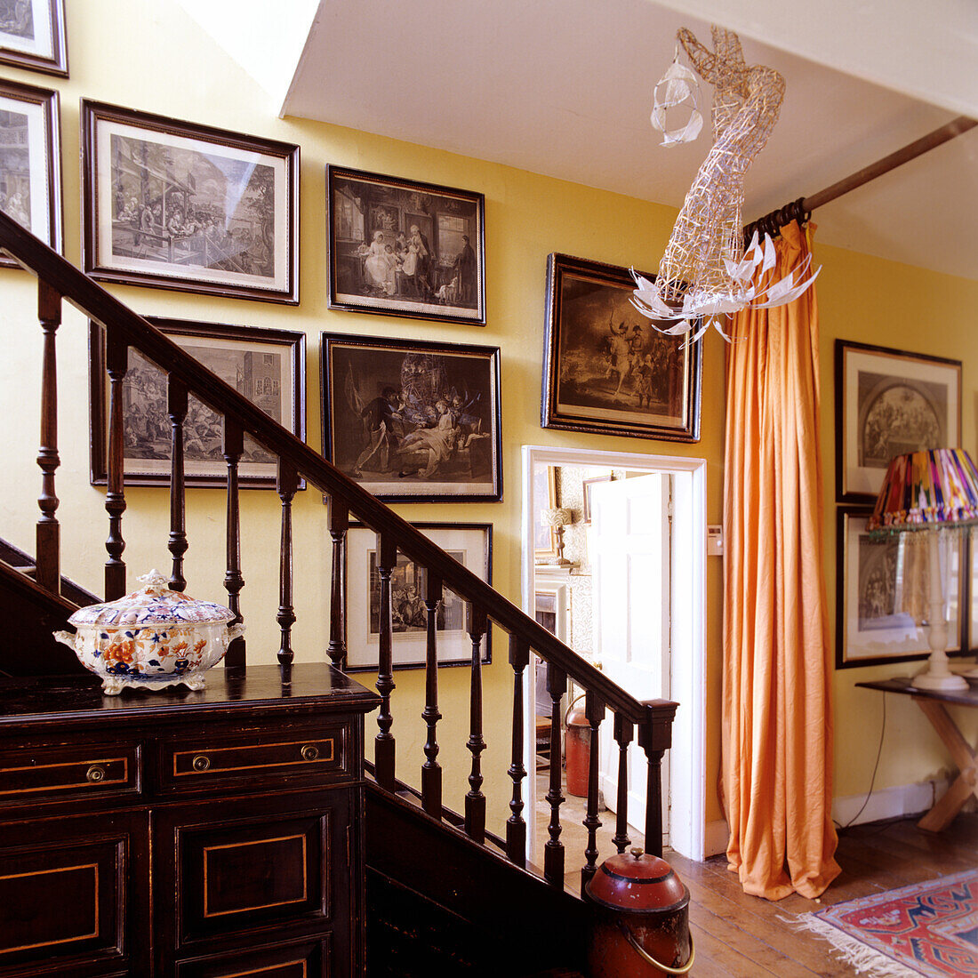 Treppenhaus mit antiker Möbelkommode und Kunstgaleriewand