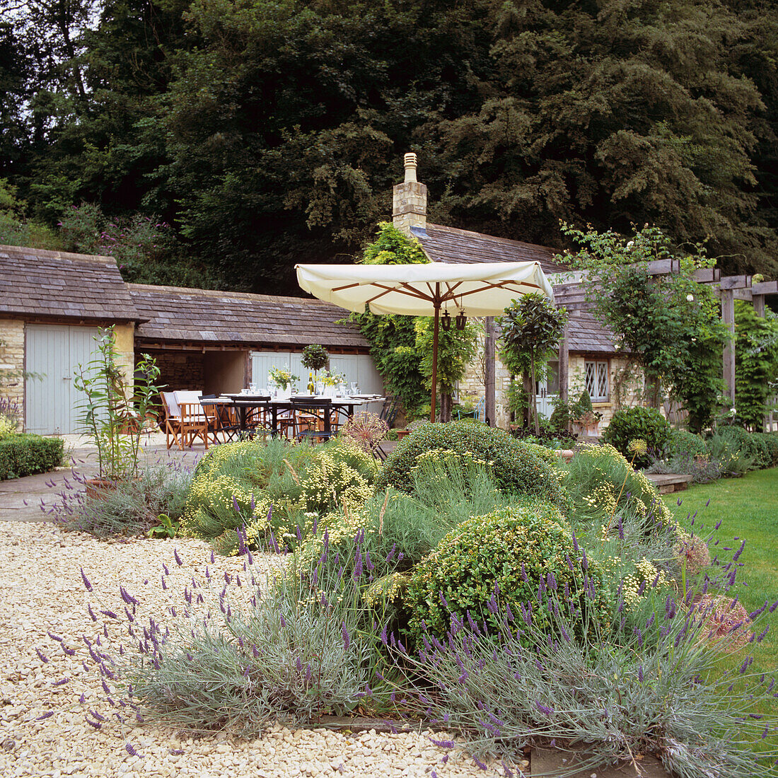 Garten mit Terasse, Lavendel und Sonnenschirm vor ländlichem Anwesen