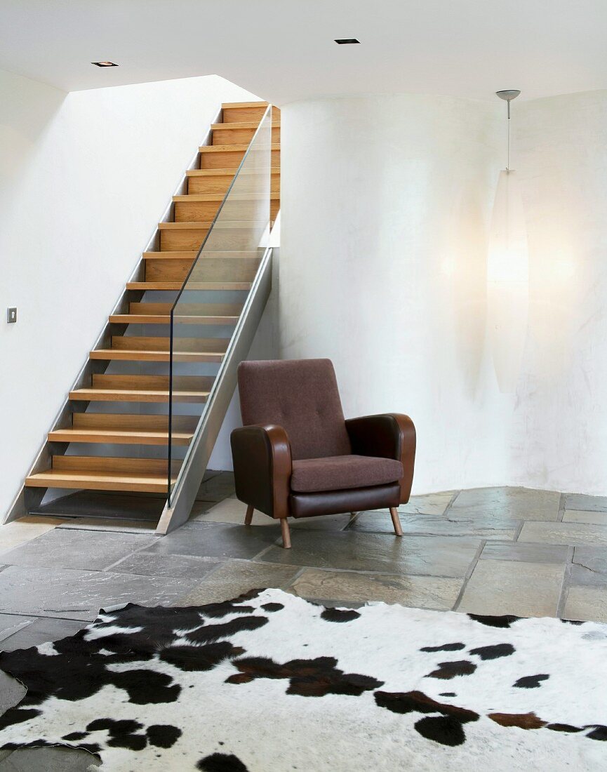 Zeitgenössische Treppe in puristischem Wohnraum mit Kuhfell auf Natursteinboden