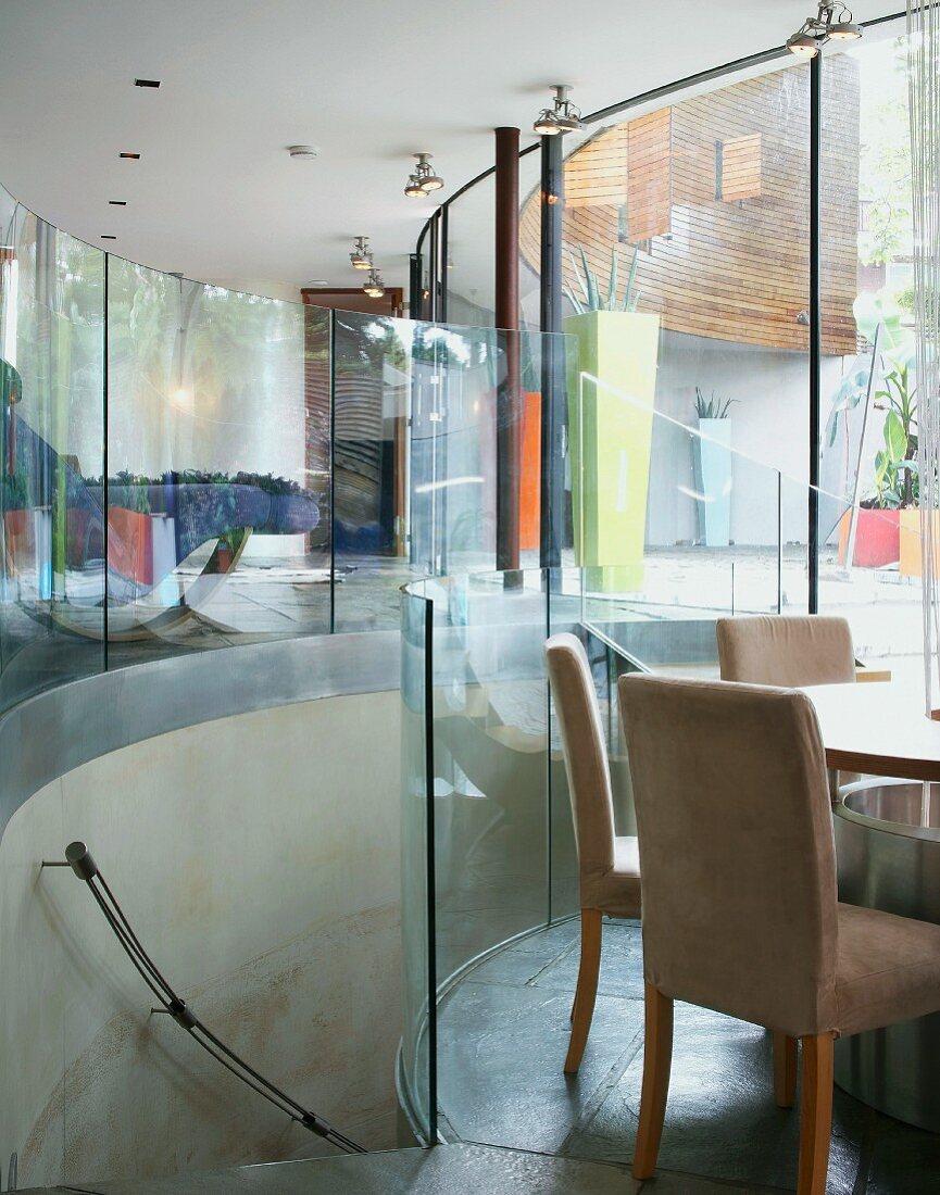 Contemporary building with semi-circular staircase and glass walls between living space and sunken dining area