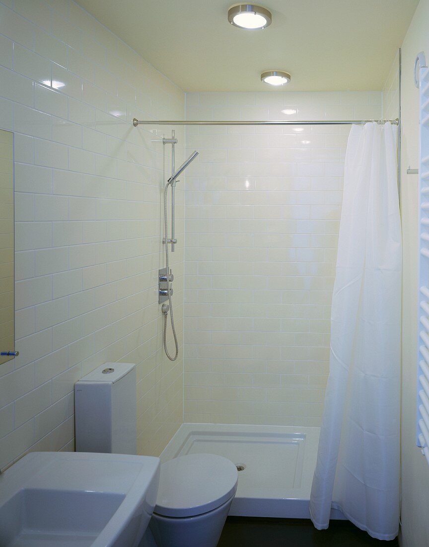 Compact configuration in a small space - cream tiles and white, modern bathroom furnishings with maritime ceiling lights