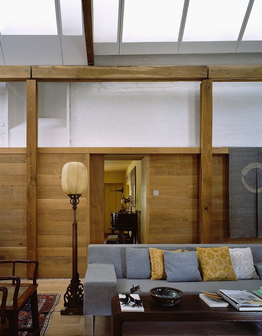 Living space in converted historic building with antique balloon lamp next to sofa and modern graphic art on wooden wall