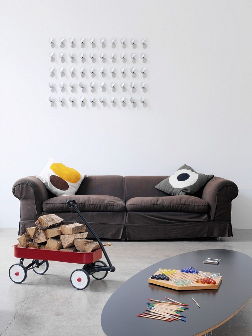Scatter cushions with graphic patterns on upholstered sofa and artwork on wall with toys in foreground