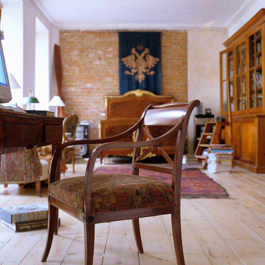 Holzboden und antike Möbel in Zimmer mit Backsteinwand