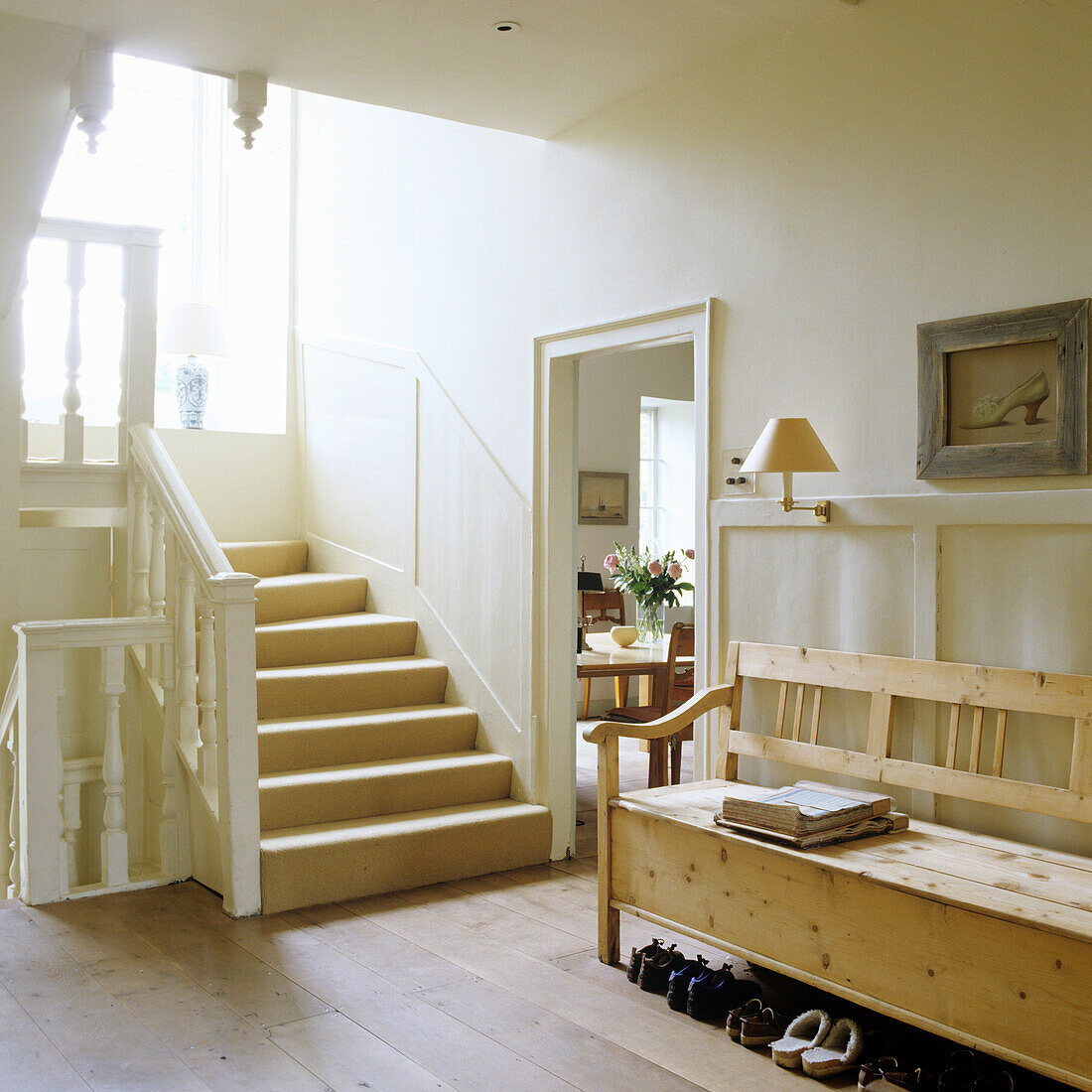 Wooden bench next to staircase in light-coloured hallway