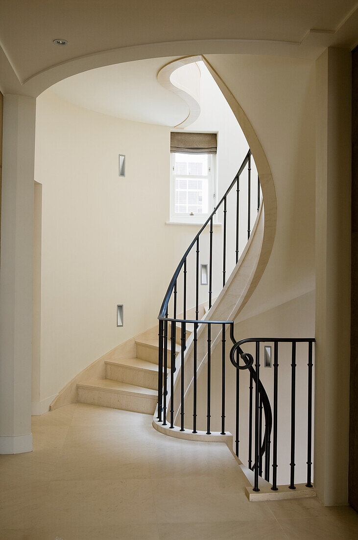 Stone staircase with black banisters in a light-coloured stairwell