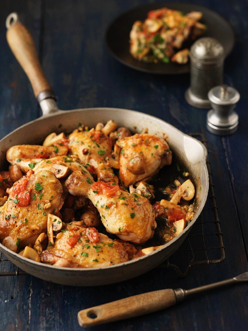 Fried chicken with tomatoes and mushrooms in a pan