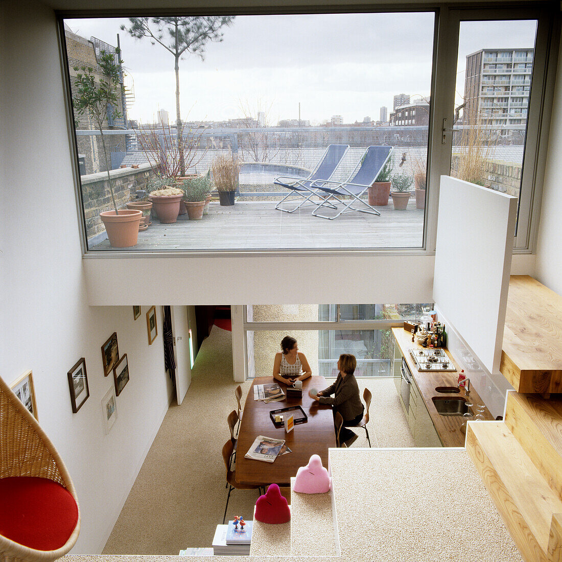 Living room with open staircase and roof terrace with deckchairs and city view