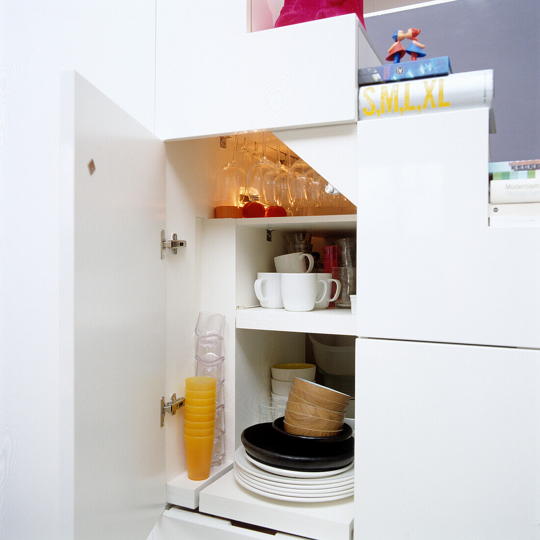 Open kitchen cupboard with plates, glasses and cups