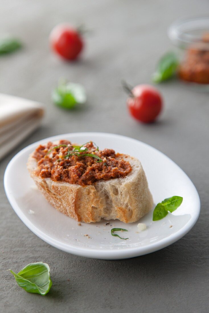 A slice of baguette topped with red pesto