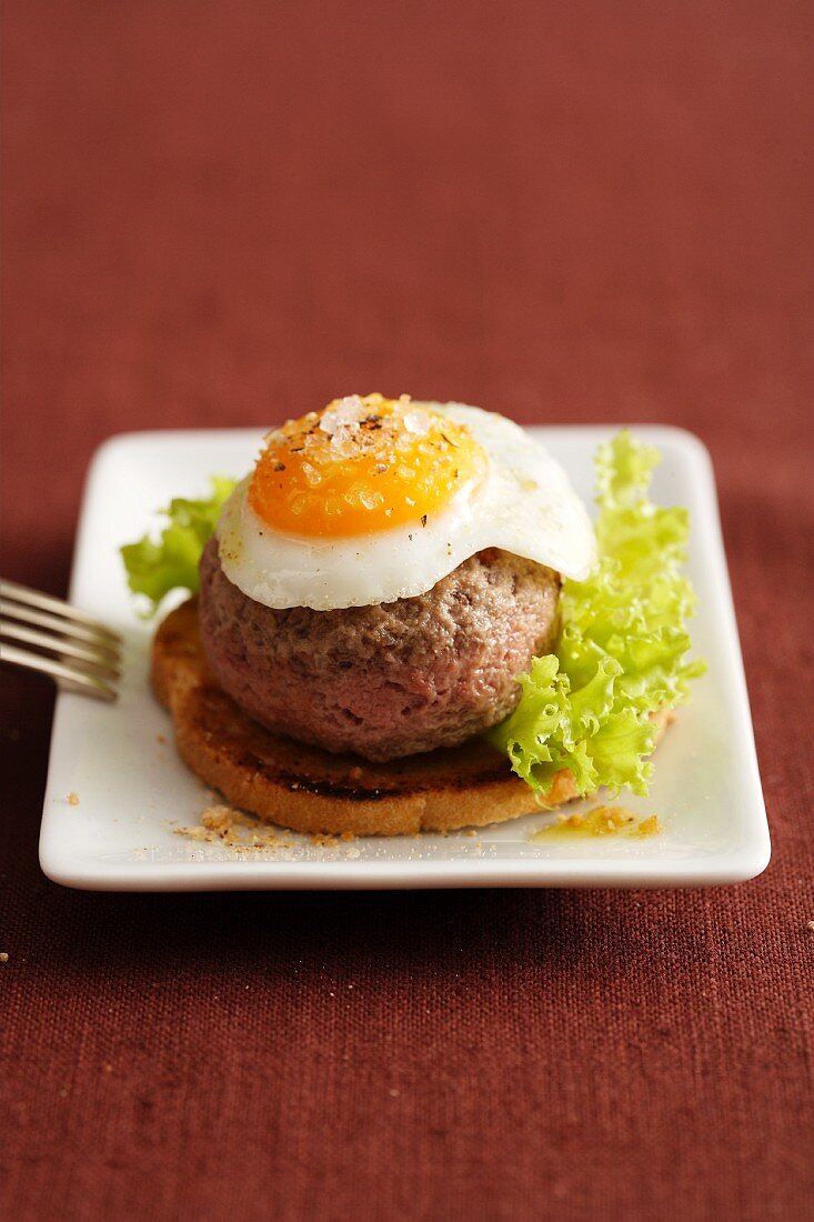 Toast topped with a burger and a fried egg