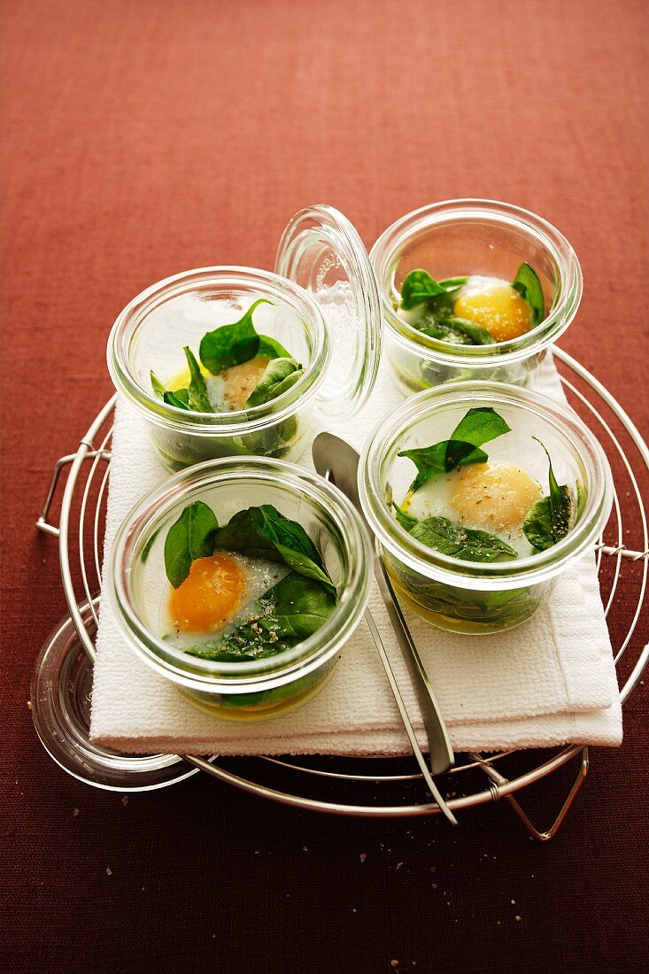 Poached quail's eggs in jars with spinach