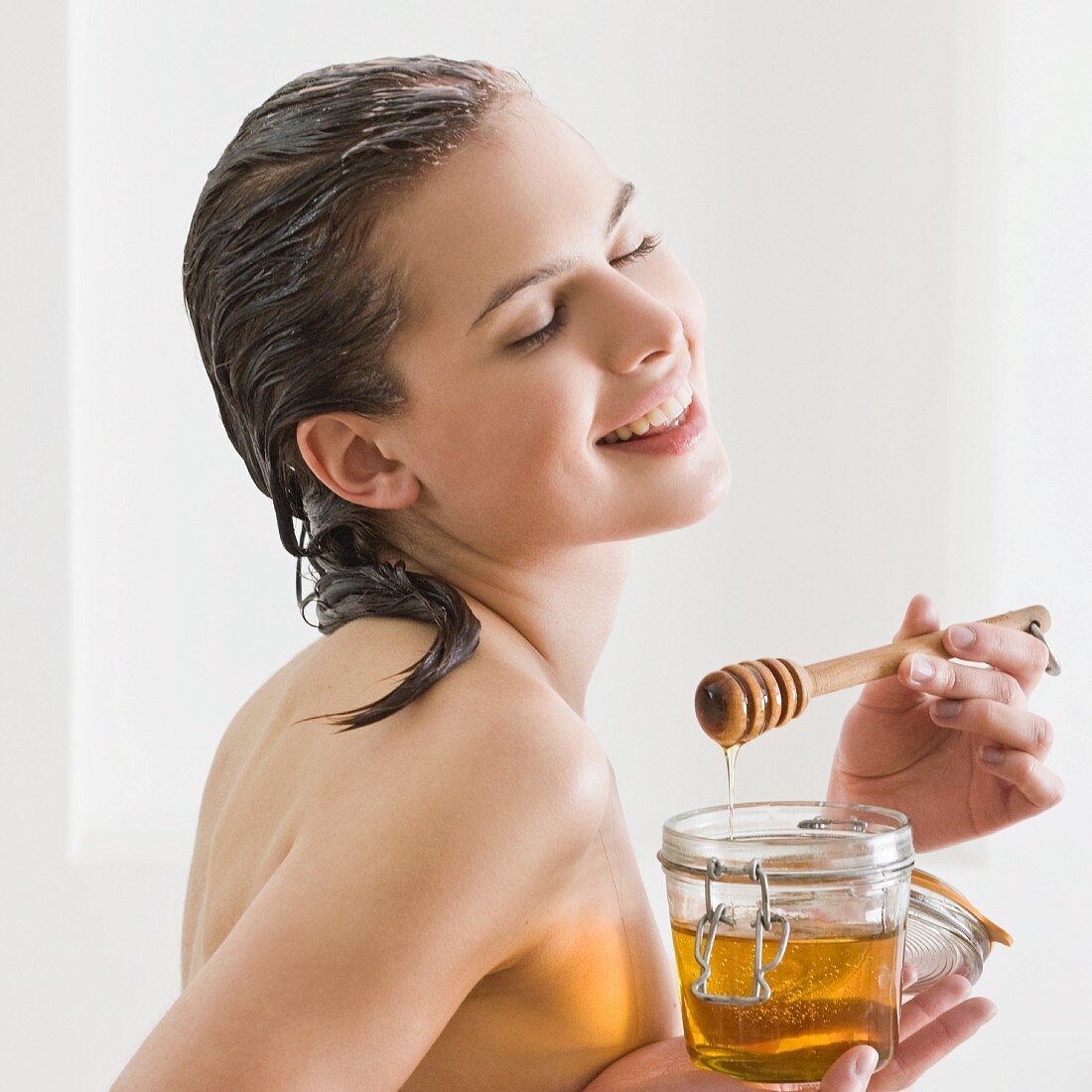 Junge Frau mit einem Glas Honig und Honig-Haarkur