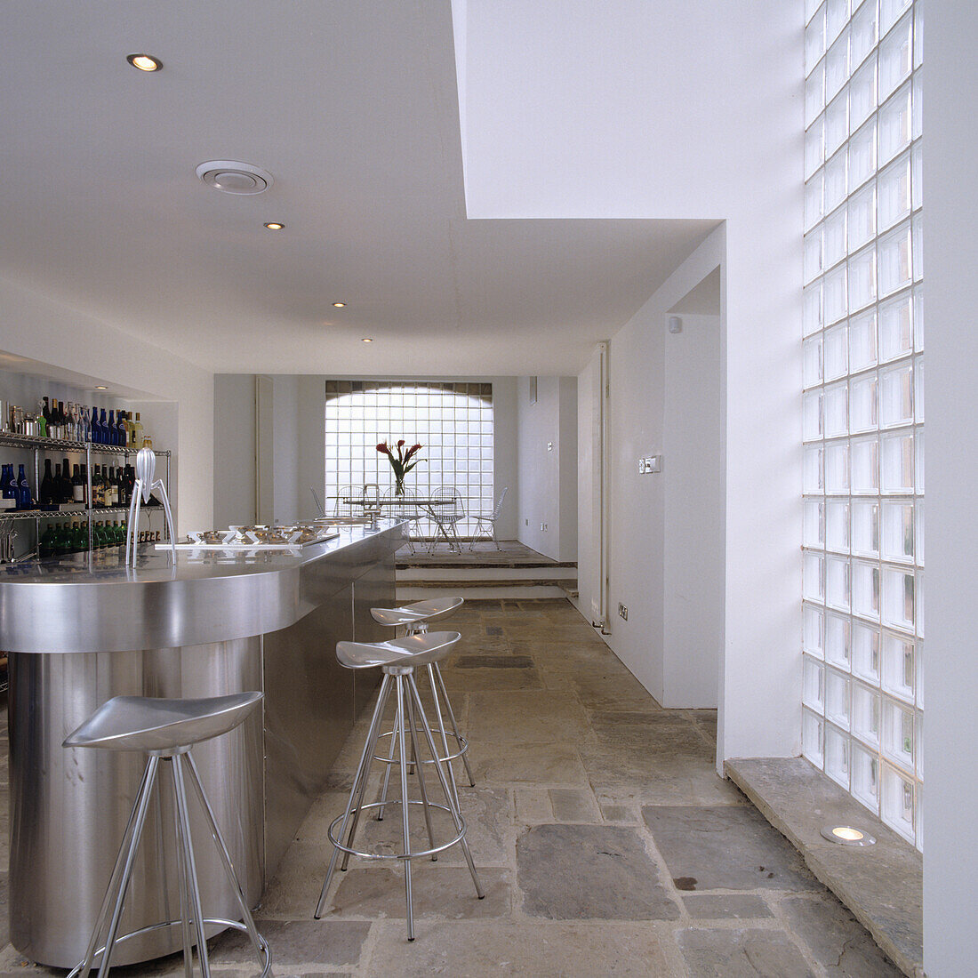 Modern kitchen with stainless steel cooking island and glass block wall