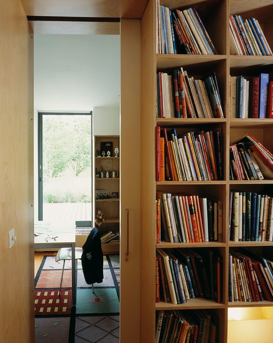 A young person's bedroom with a patterned rug in front of a floor-to-ceiling bookshelf