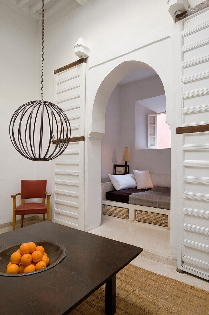 Table, hanging lamp and fruit bowl, oriental-style passageway to cosy seating area