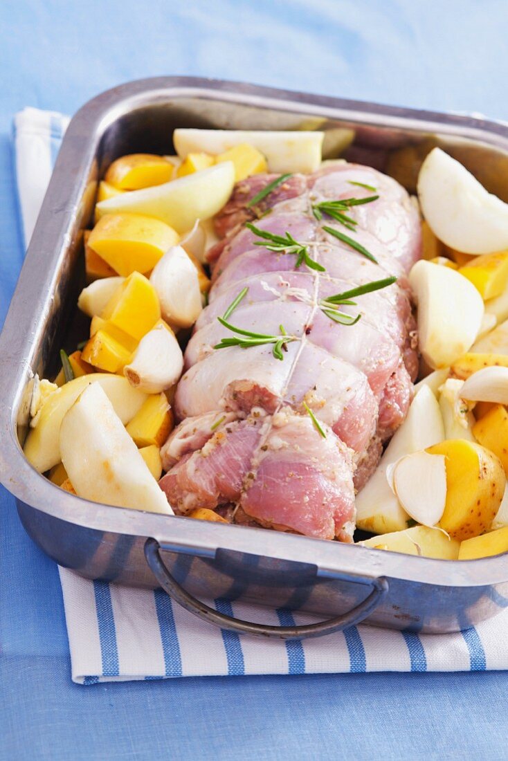 Turkey roulade in a roasting tin with garlic, potatoes and pears