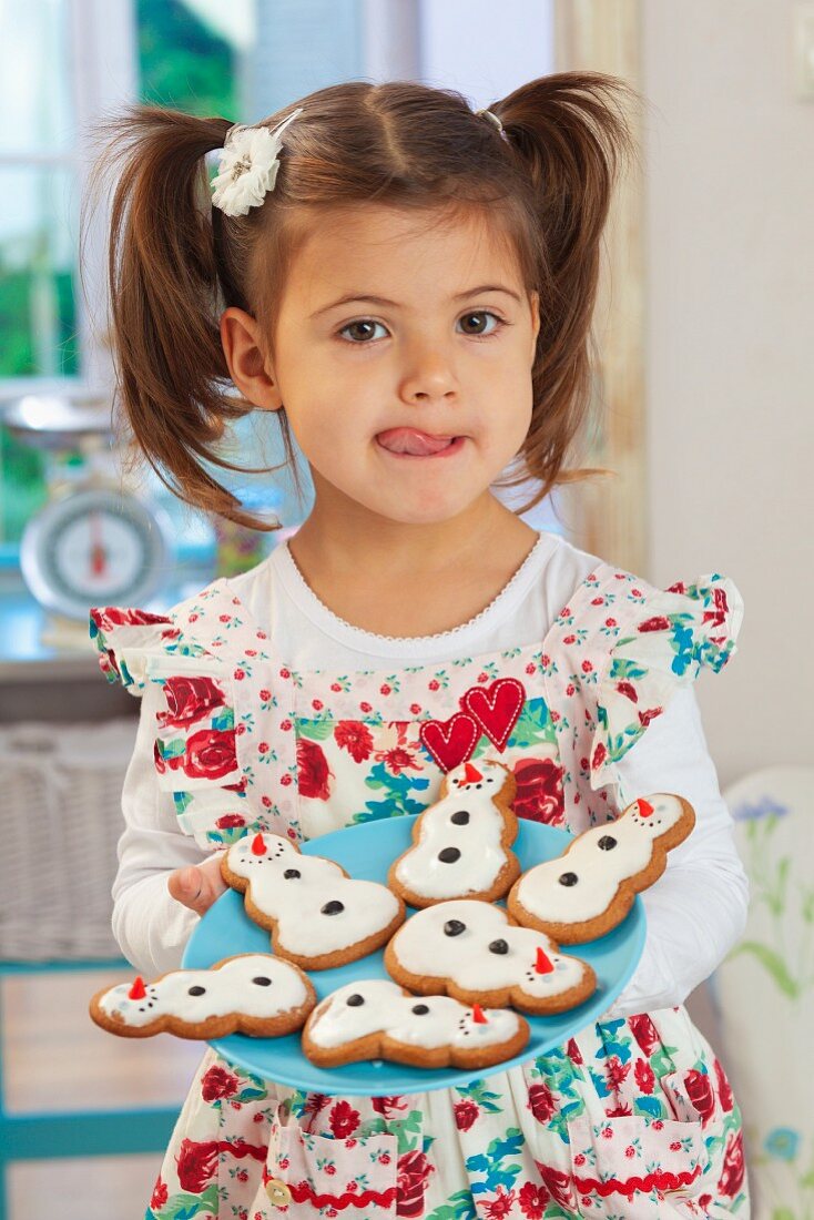 A little girl holding a plate of gingerbread snowmen