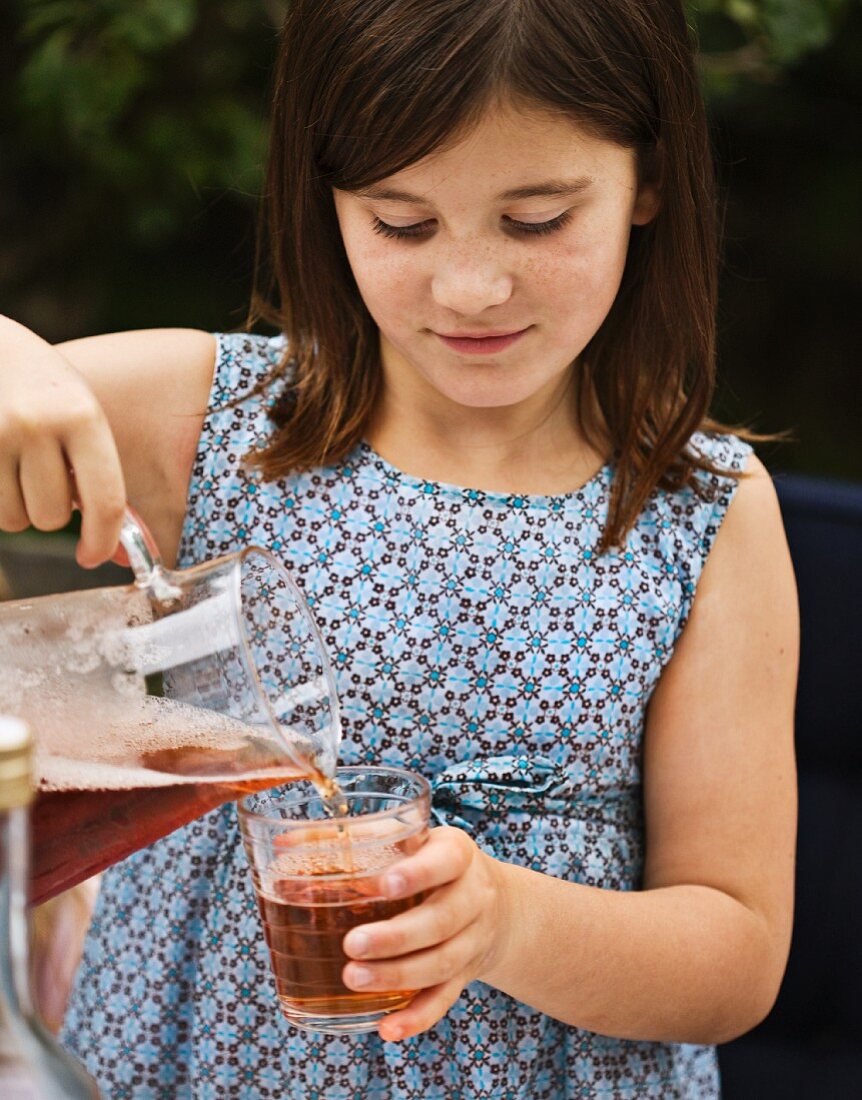 A girl pouring juice from a jug into a glass