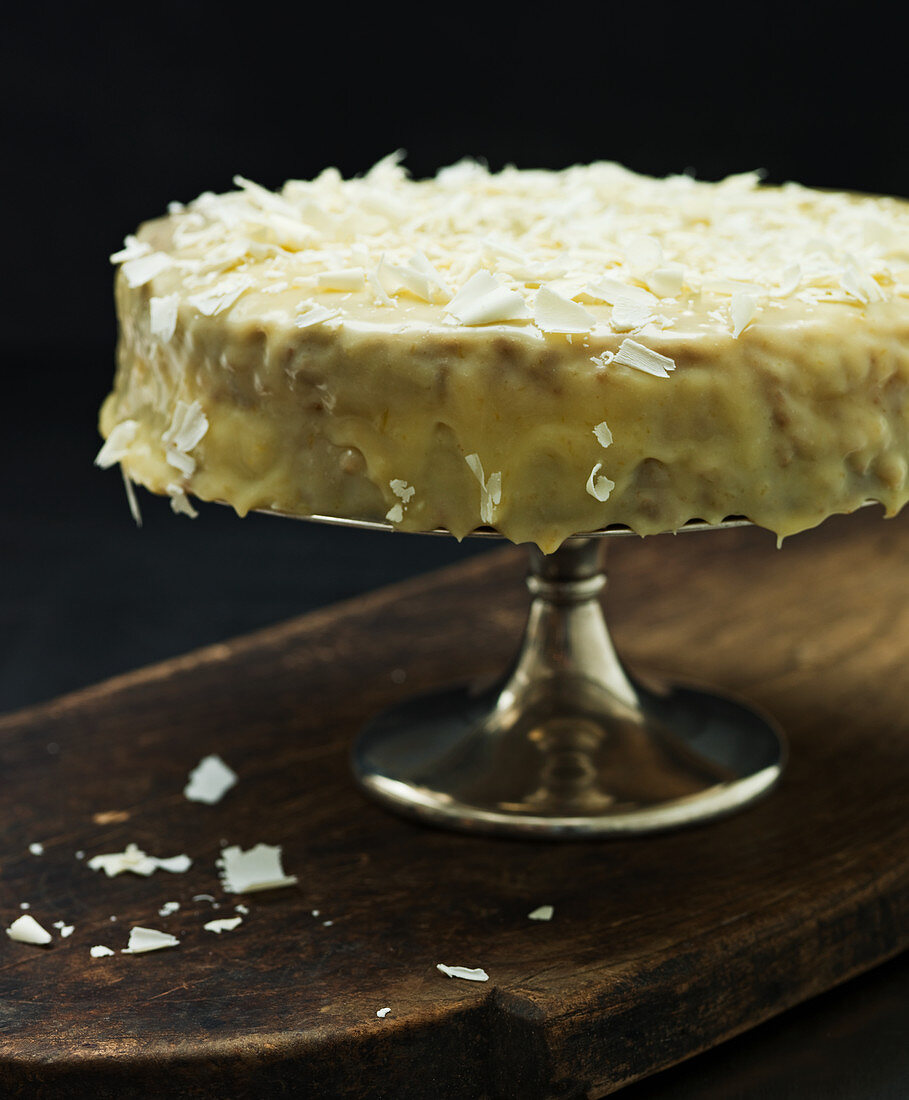 A lemon cake topped with white chocolate on a cake stand