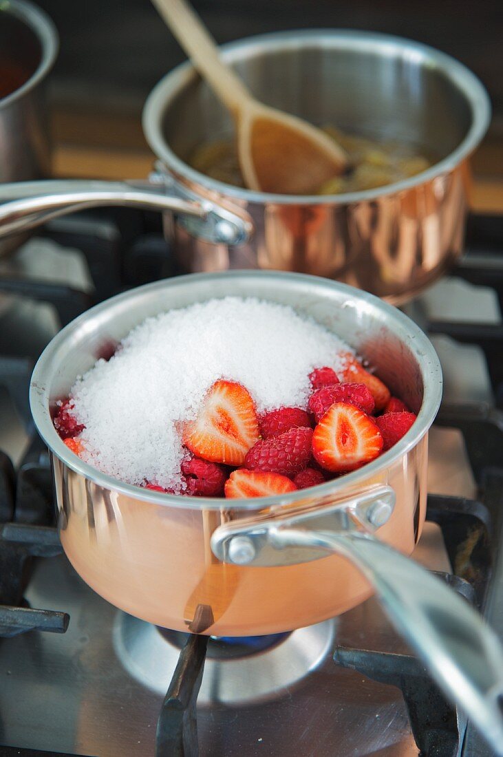 Jam making: A pot of fruit and preserving sugar on a hob