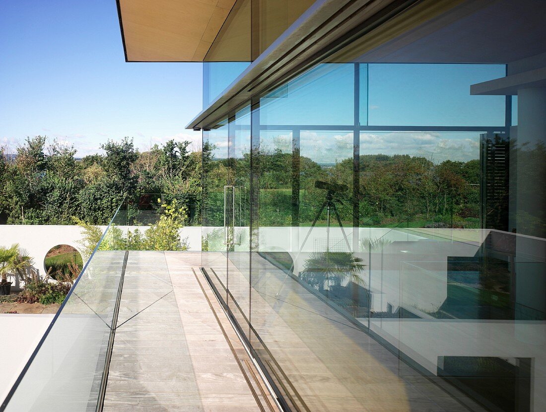 Encircling terrace against glass facade of contemporary house with view of garden