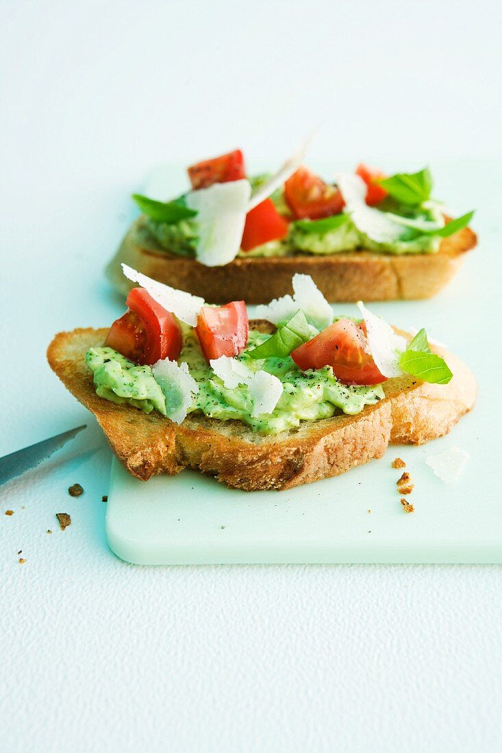 Bread topped with basil spread, tomatoes and parmesan cheese