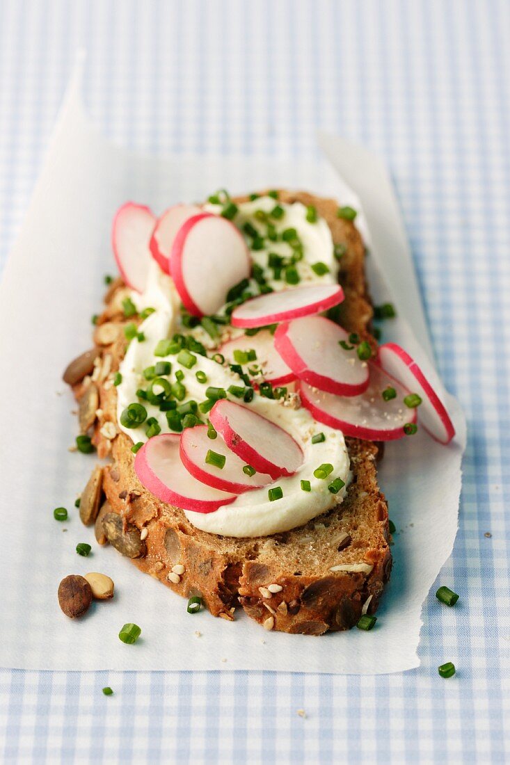 A slice of wholemeal bread topped with cream cheese and radishes
