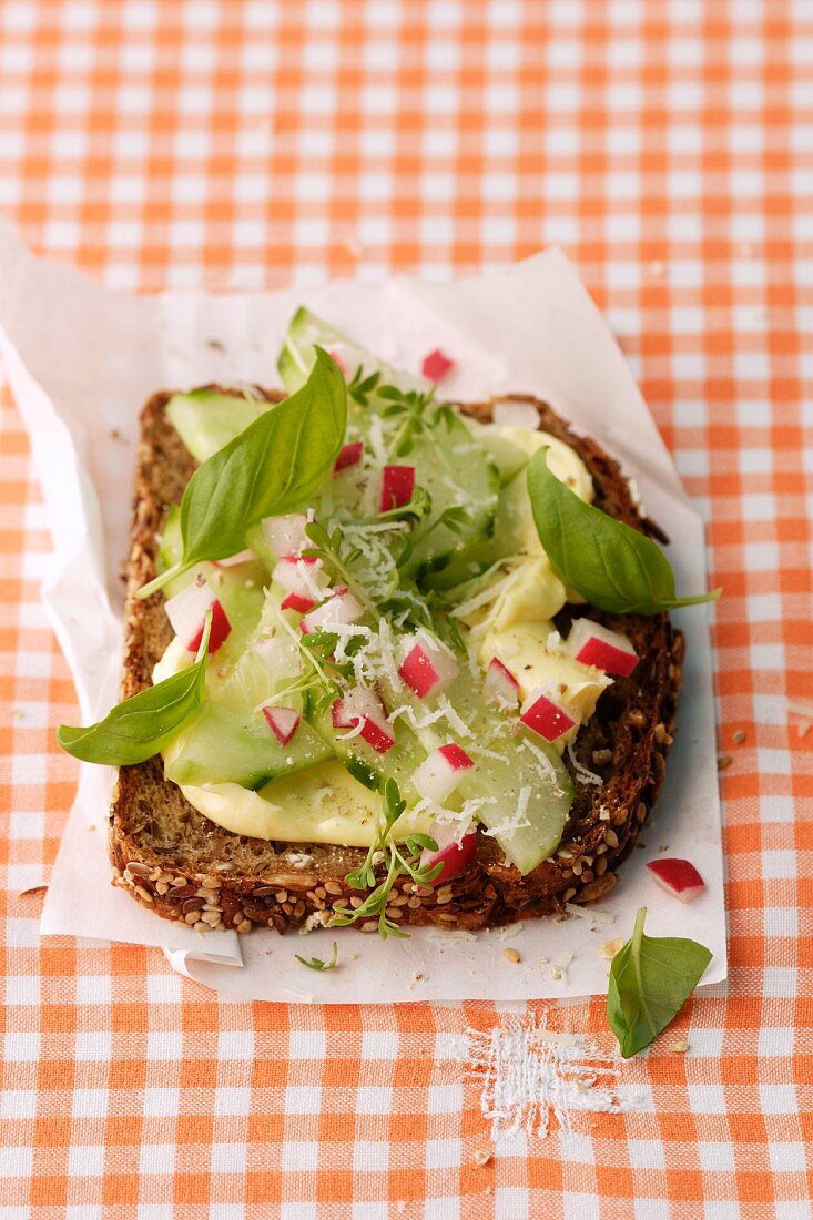 A slice of wholemeal bread topped with cucumber, radishes and basil