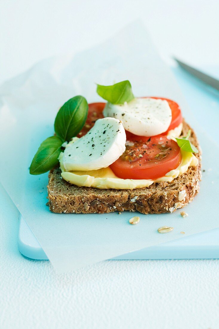 A slice of wholemeal bread topped with tomatoes, mozzarella and basil