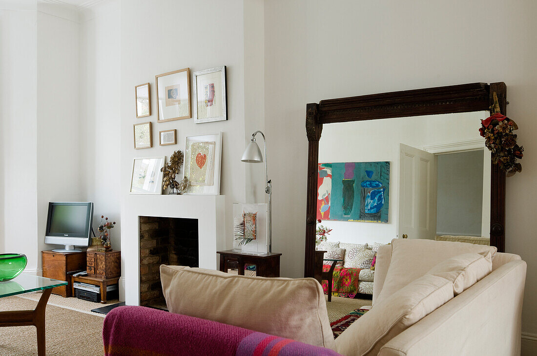 Living room with light-coloured couch, large mirror and pictures