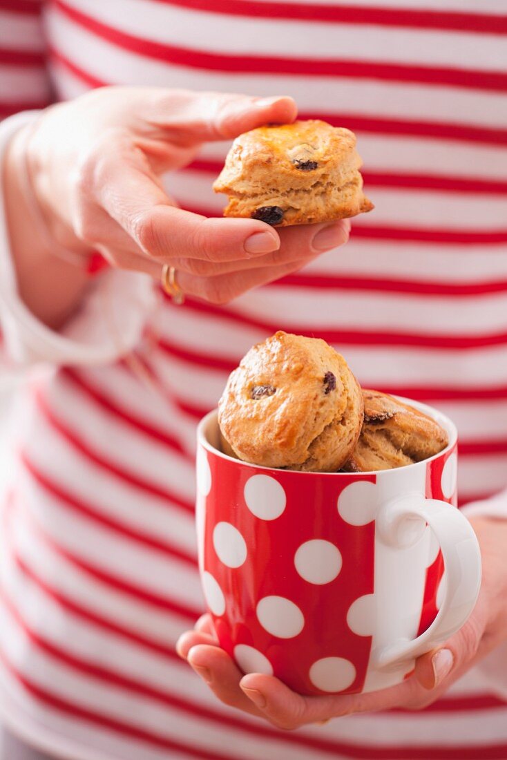 Frau hält Tasse mit Safran-Scones