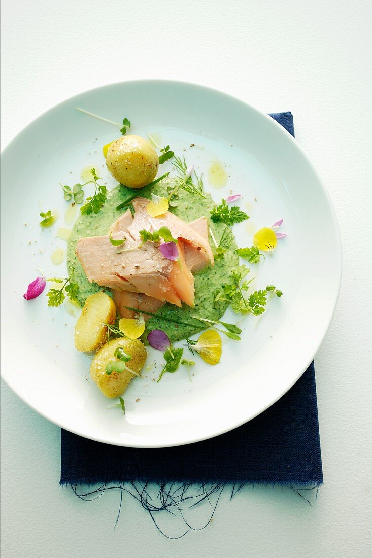 Salmon fillet with herb sauce, edible flowers and potatoes