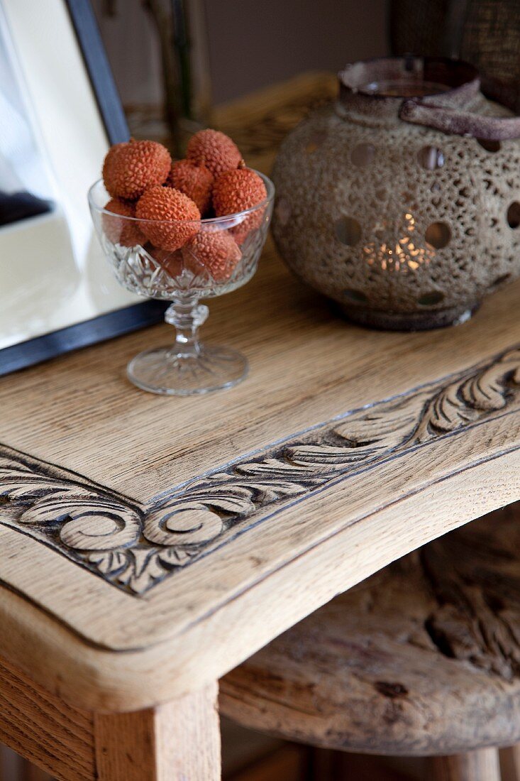 Lychees in crystal bowl and Chinese candle lantern on carved wooden table top