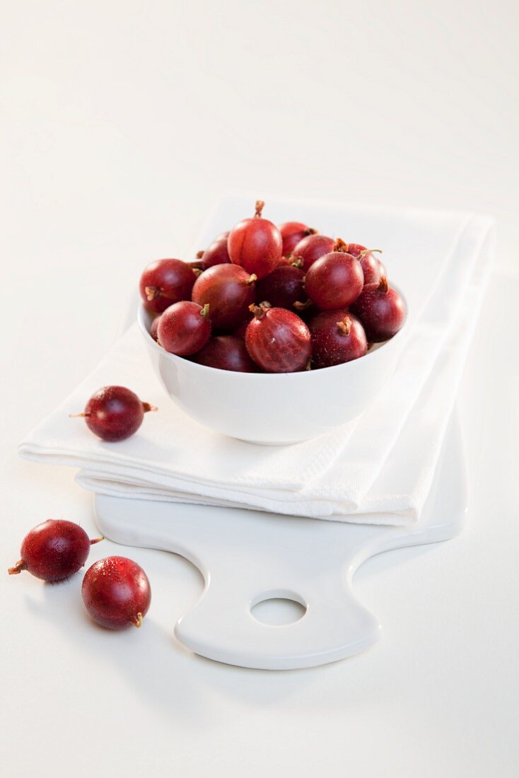 A bowl of red gooseberries on a napkin