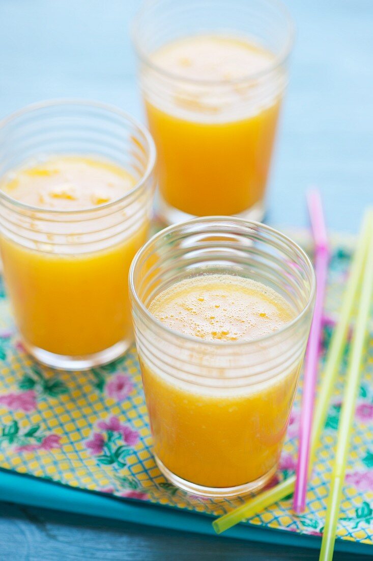 Drei Gläser mit Smoothies (Mango, Orange, Passionsfrucht)