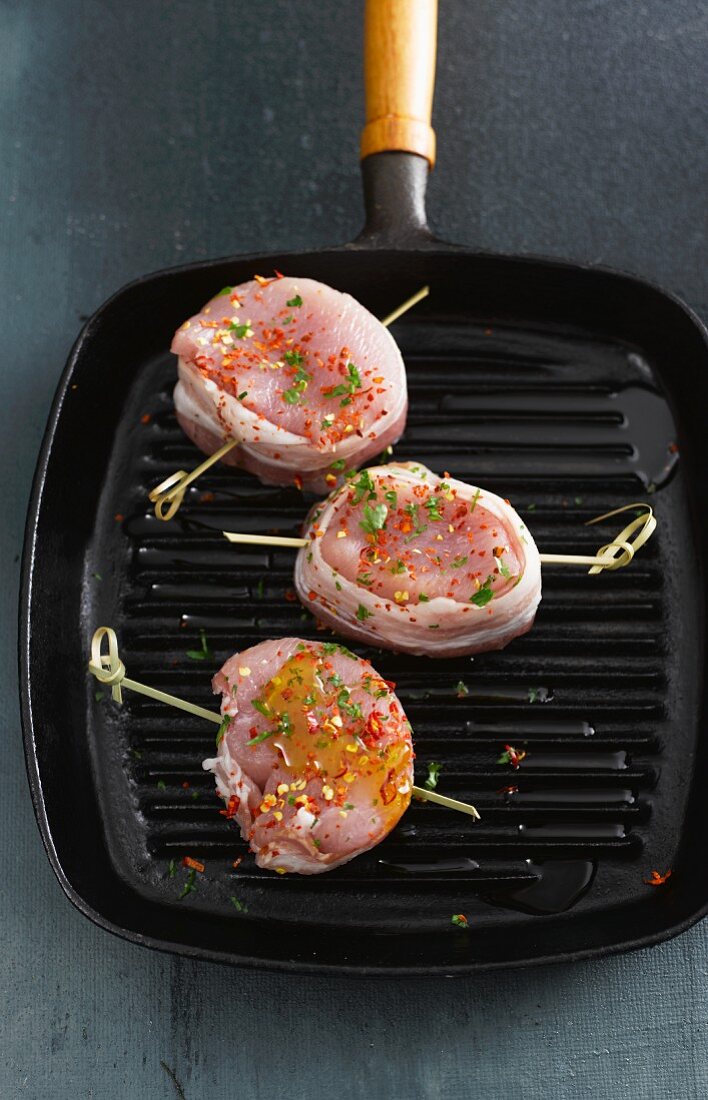 Pork medallions wrapped in bacon in a pan